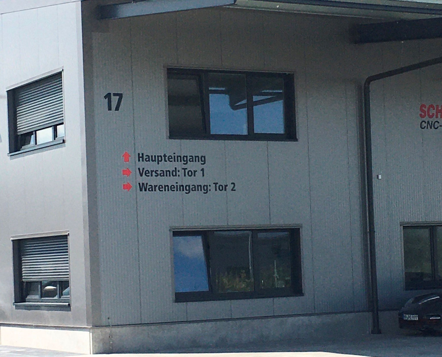 Haupteingang der Firma Schnabel CNC-Fertigung GmbH mit Wegweiser zu den verschiedenen Werksbereichen